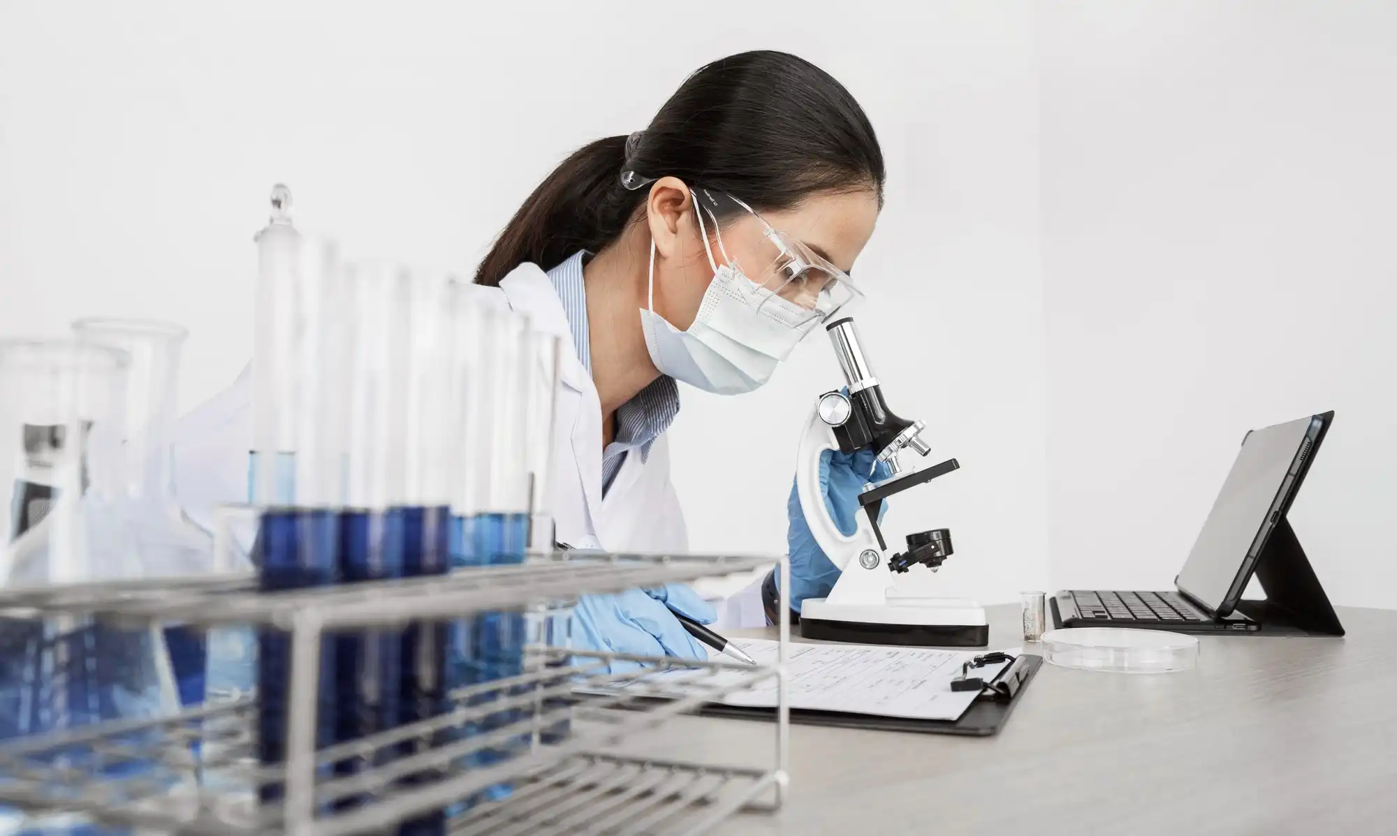 一名实验员正在显微镜下进行分析，这象征着企业必须遵循GB/T 14233.1-2022 化学分析方法新规，以确保产品检测合规。